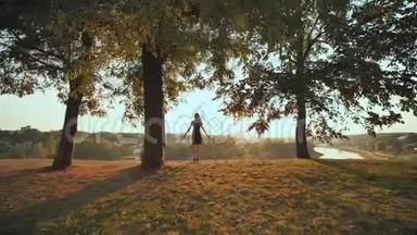 女孩热情地跑去迎接城市背景上的日落，举起双手。 录像正在播放。